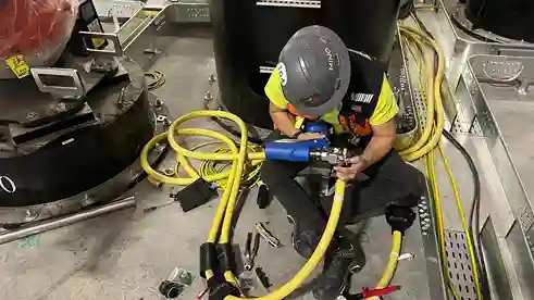 Electrical technician drilling and adjusting wiring in industrial facility