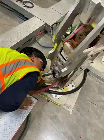 Engineer inspecting robot installation from below in automation line